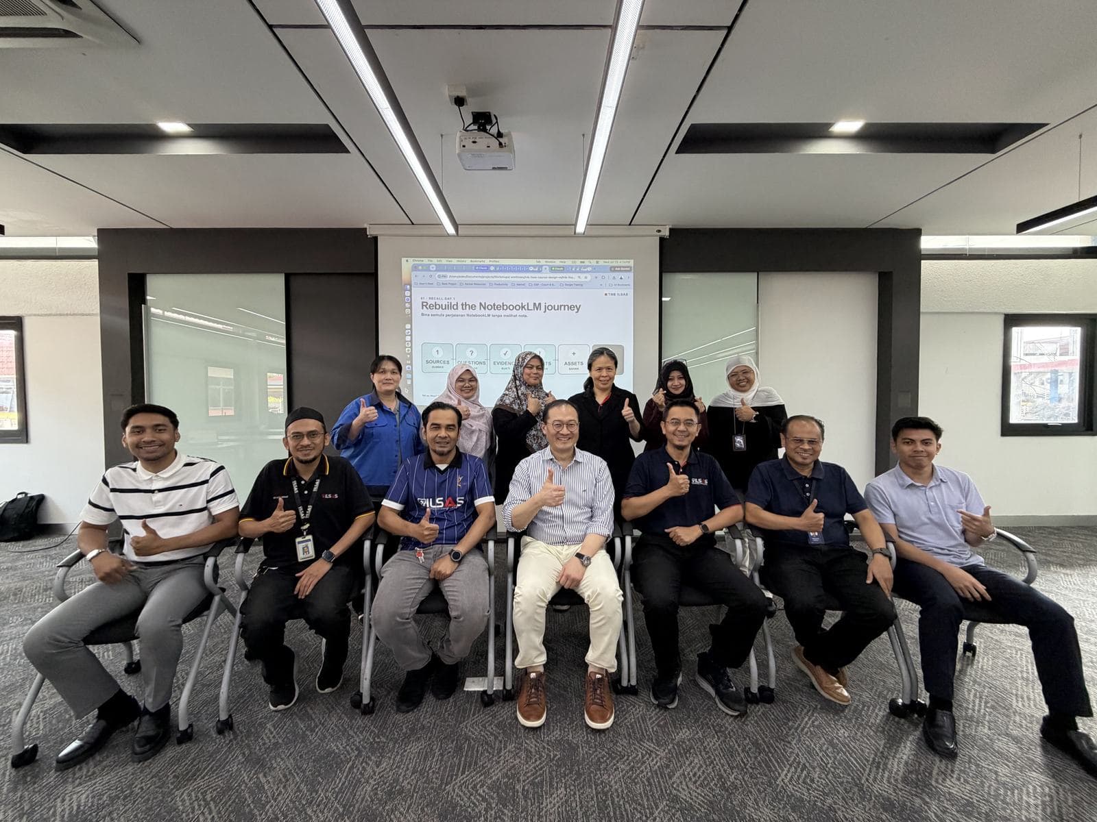 Group photo of workshop participants seated together in a training room, giving a thumbs-up