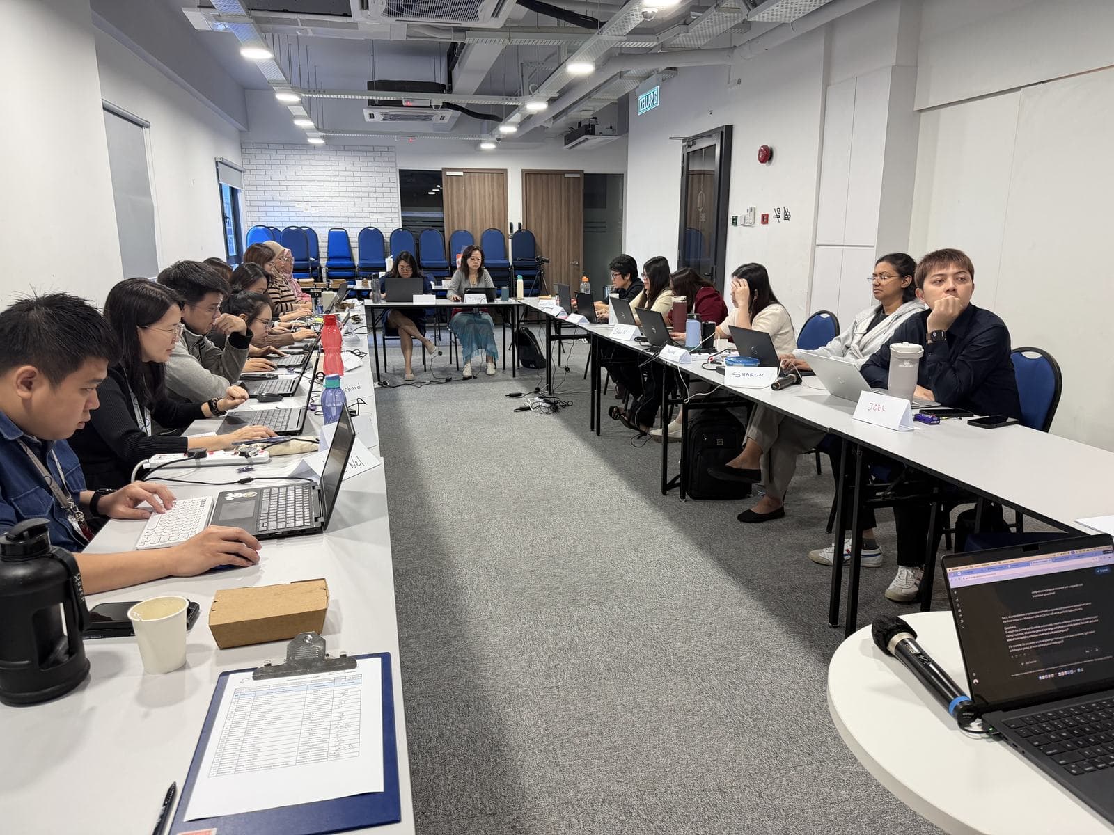Participants working on laptops along long tables during a hands-on AI workshop session